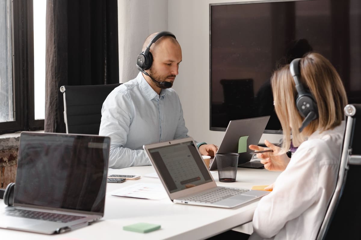 Two support agents wearing headsets working at laptops